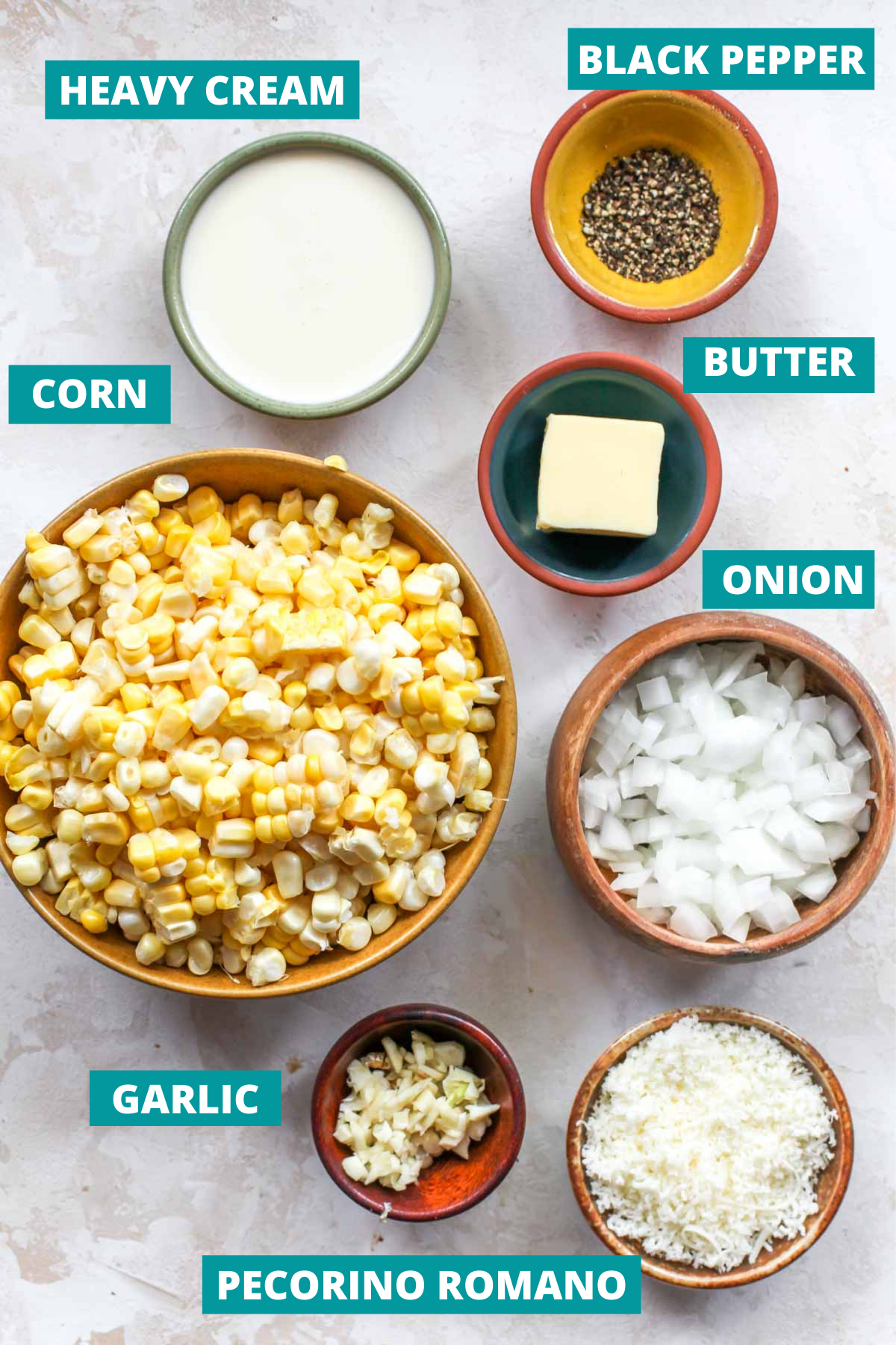 Corn, cheese, butter, and black pepper in separate bowls with blue ingredient label tags