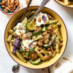 Pesto pasta with zucchini and mushrooms in a yellow bowl