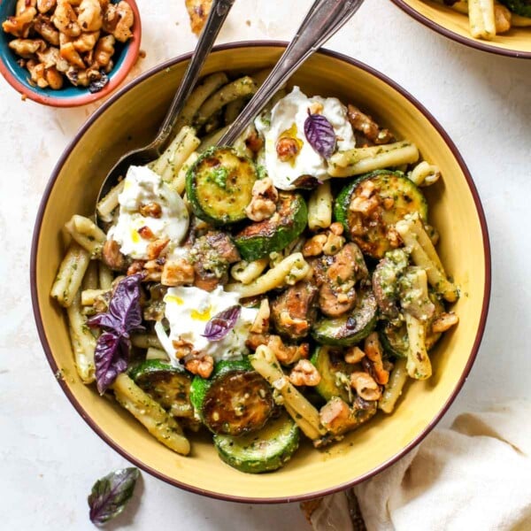 Pesto pasta with zucchini and mushrooms in a yellow bowl