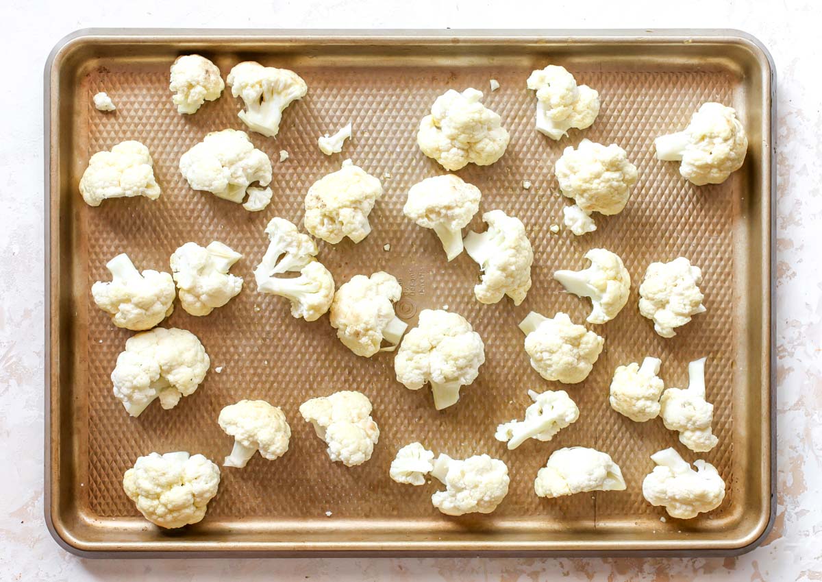 Cauliflower florets on a gold baking sheet