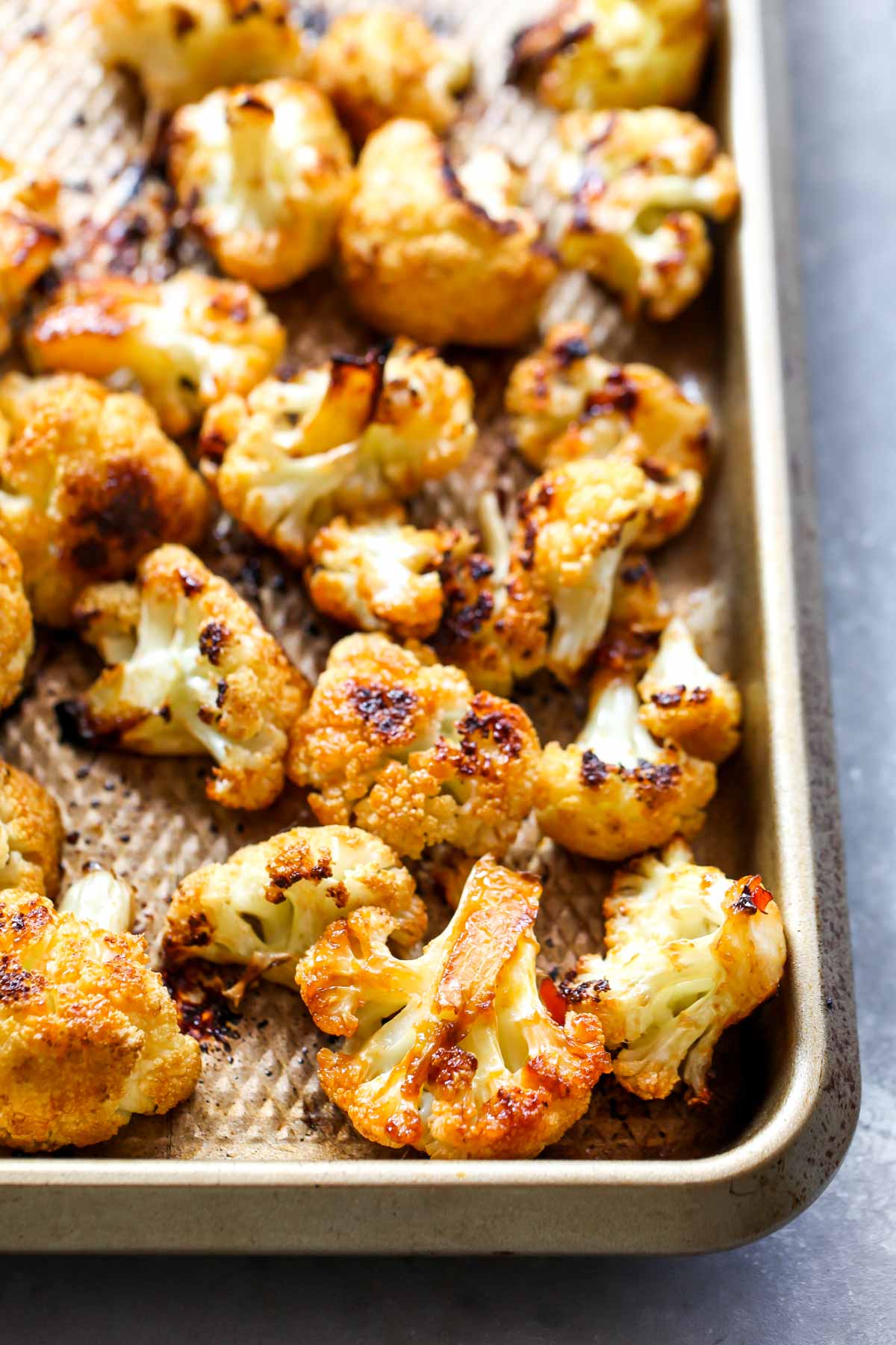 Roasted cauliflower florets on a gold baking sheet