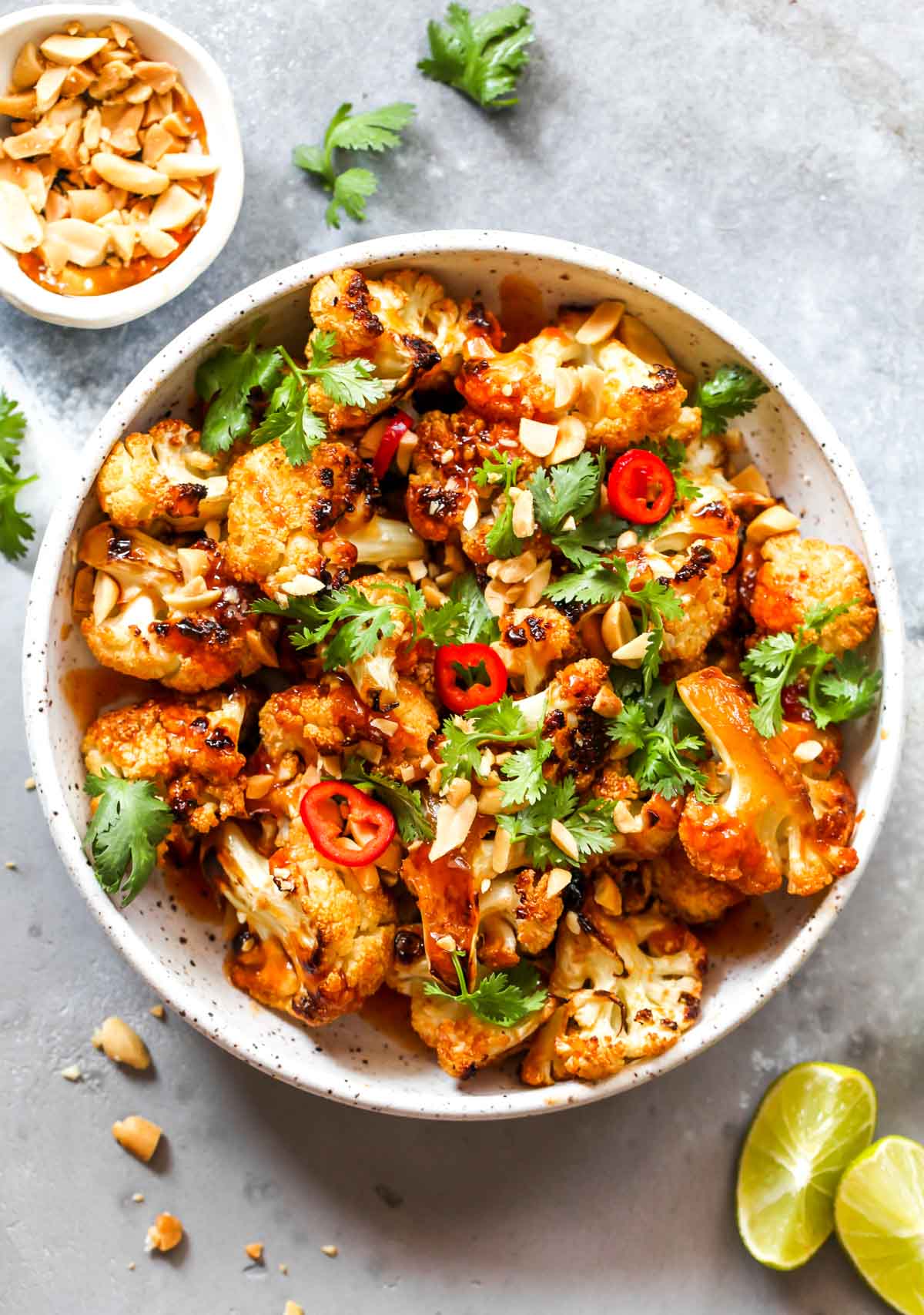 Roasted cauliflower topped with peanuts and cilantro in a white bowl