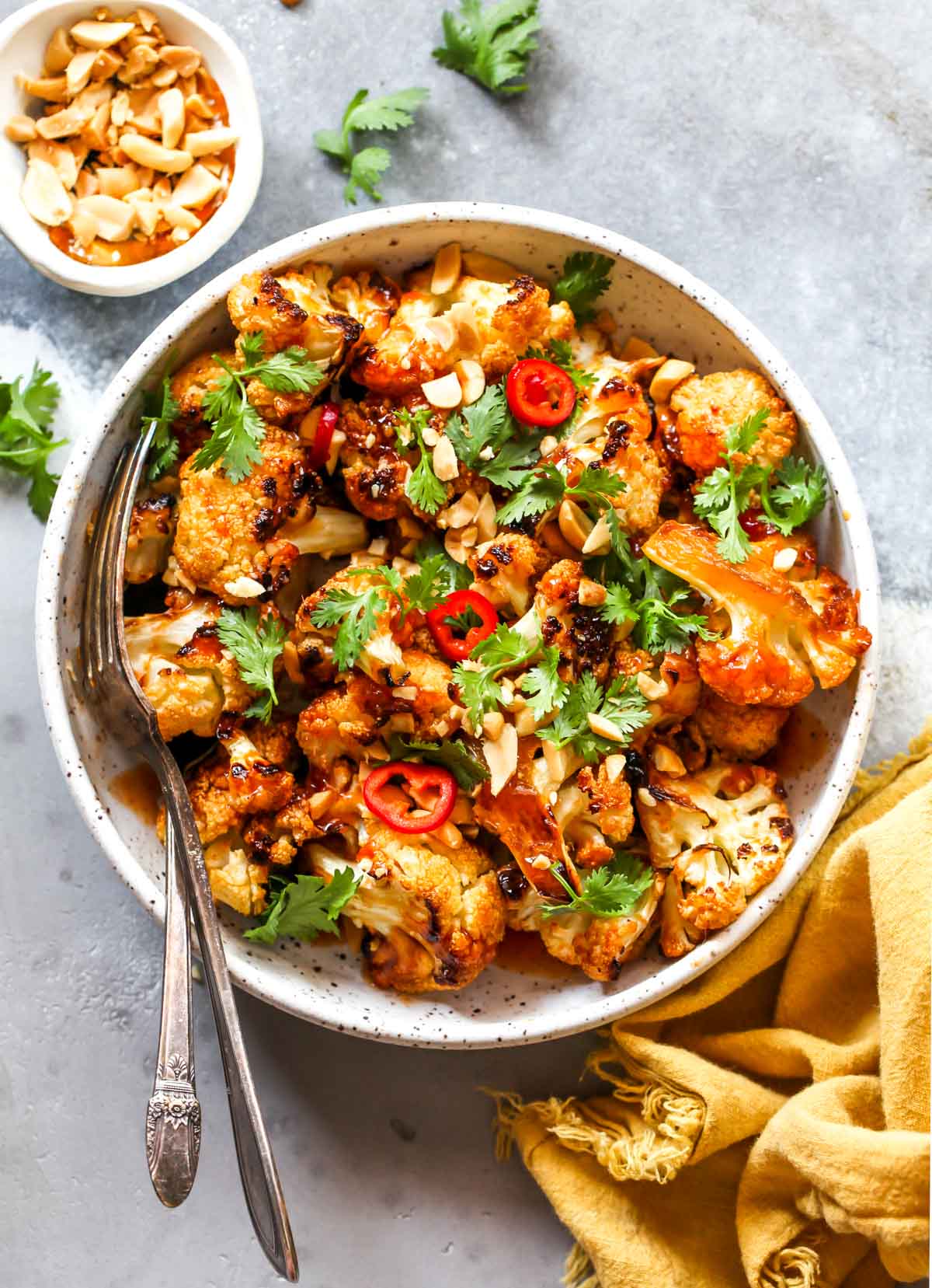Spoon and fork sticking in a bowl of roasted cauliflower