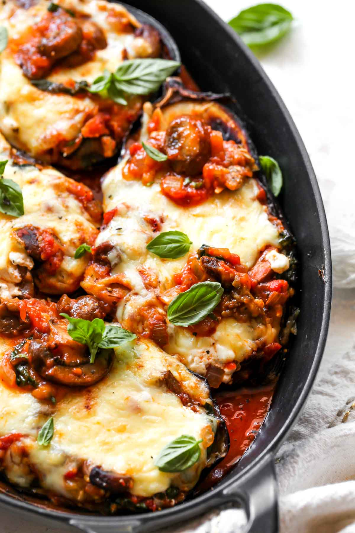 Eggplant lasagna boats in a baking pan topped with basil.