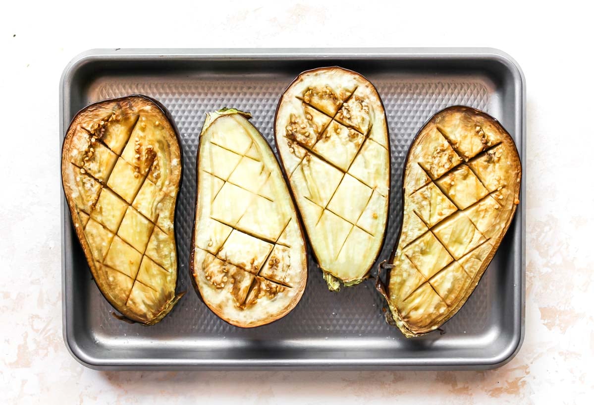 Sliced eggplant halves on a silver sheet pan