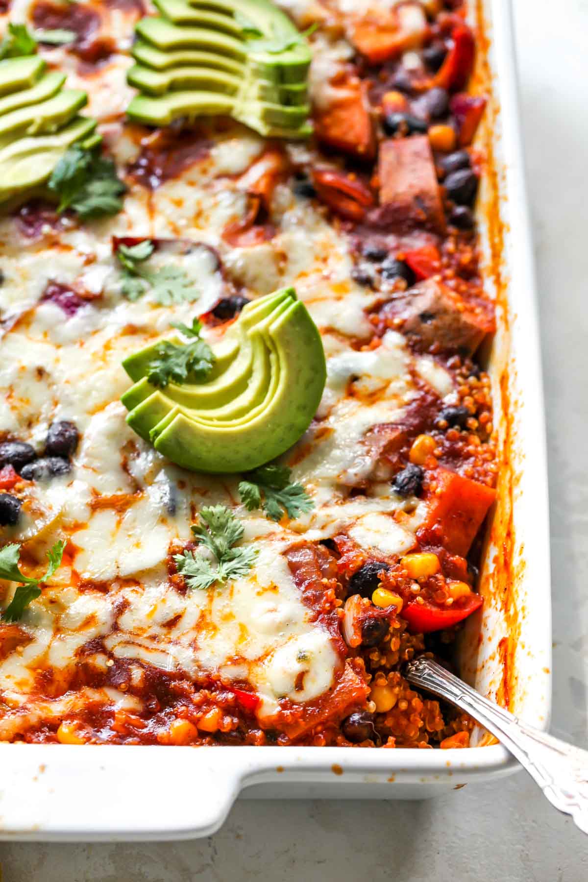 Serving spoon in the corner of a pan of vegetarian enchiladas