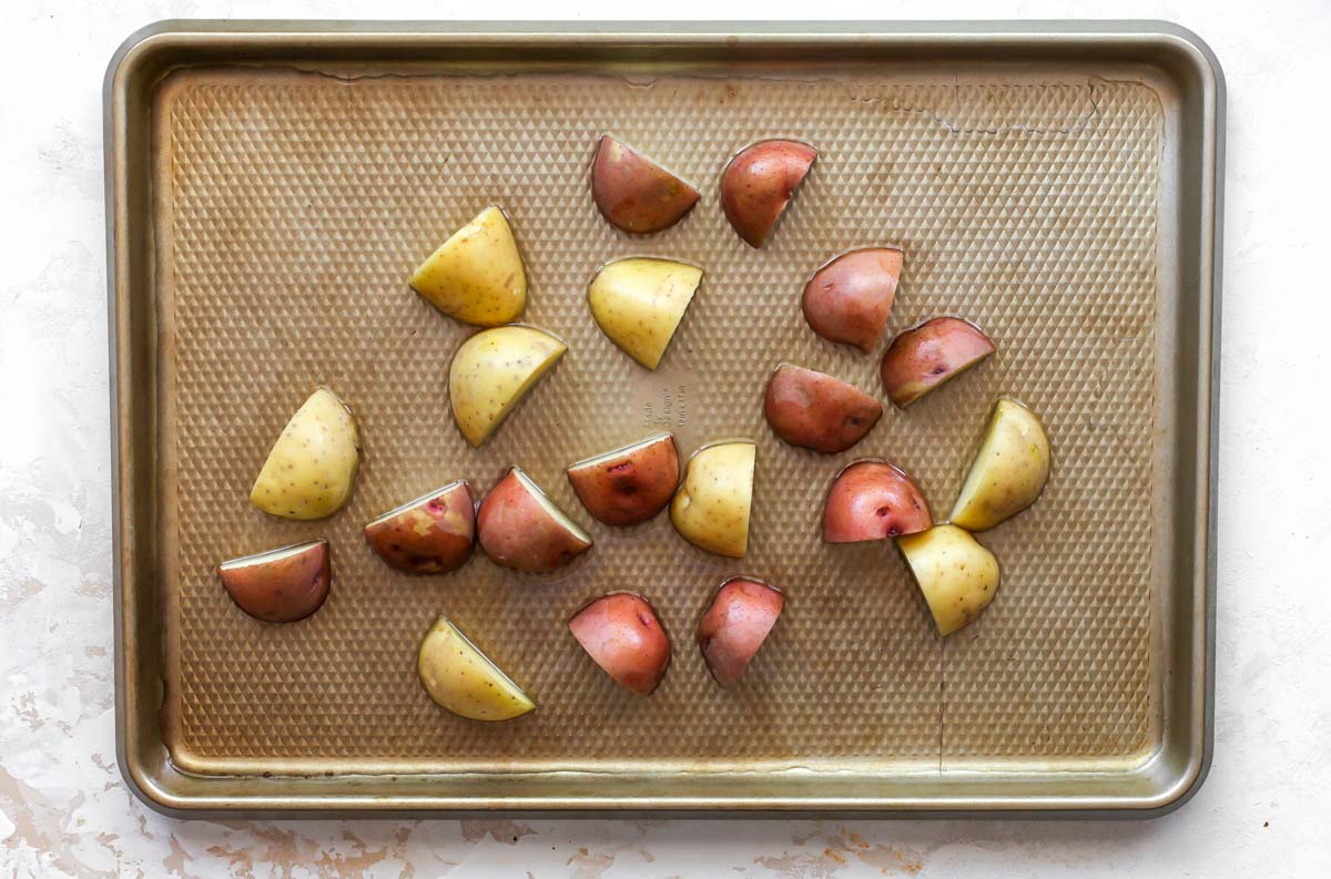 Chopped potatoes on a gold baking sheet