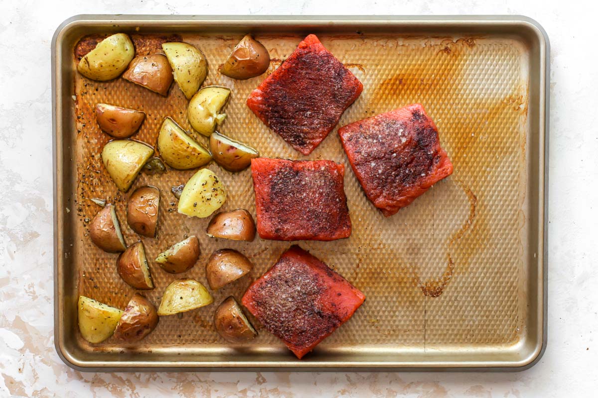 Potatoes and salmon fillets on a gold sheet pan