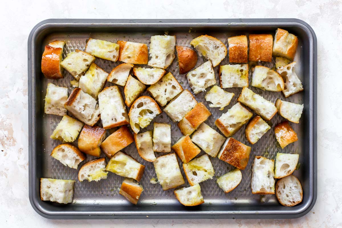 Cubed bread on a sheet pan tossed in olive oil, salt, and pepper prior to toasting.