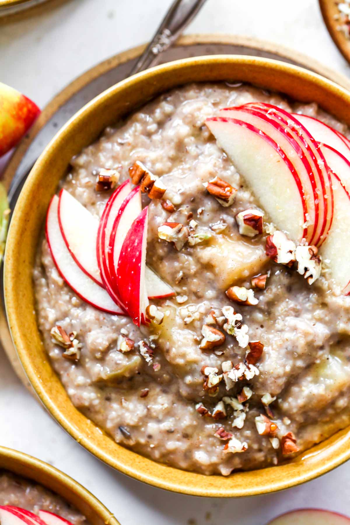 Close up of apple oats in a gold bowl topped with pecans