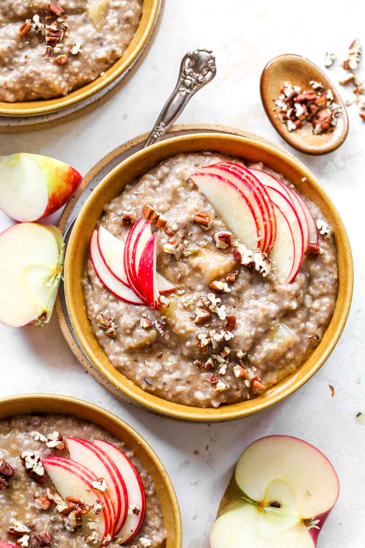 Slow cooker oatmeal in gold bowls with sliced apple topping