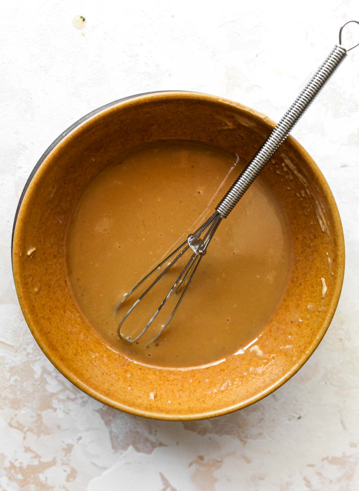 Maple vinaigrette being whisked in a gold bowl