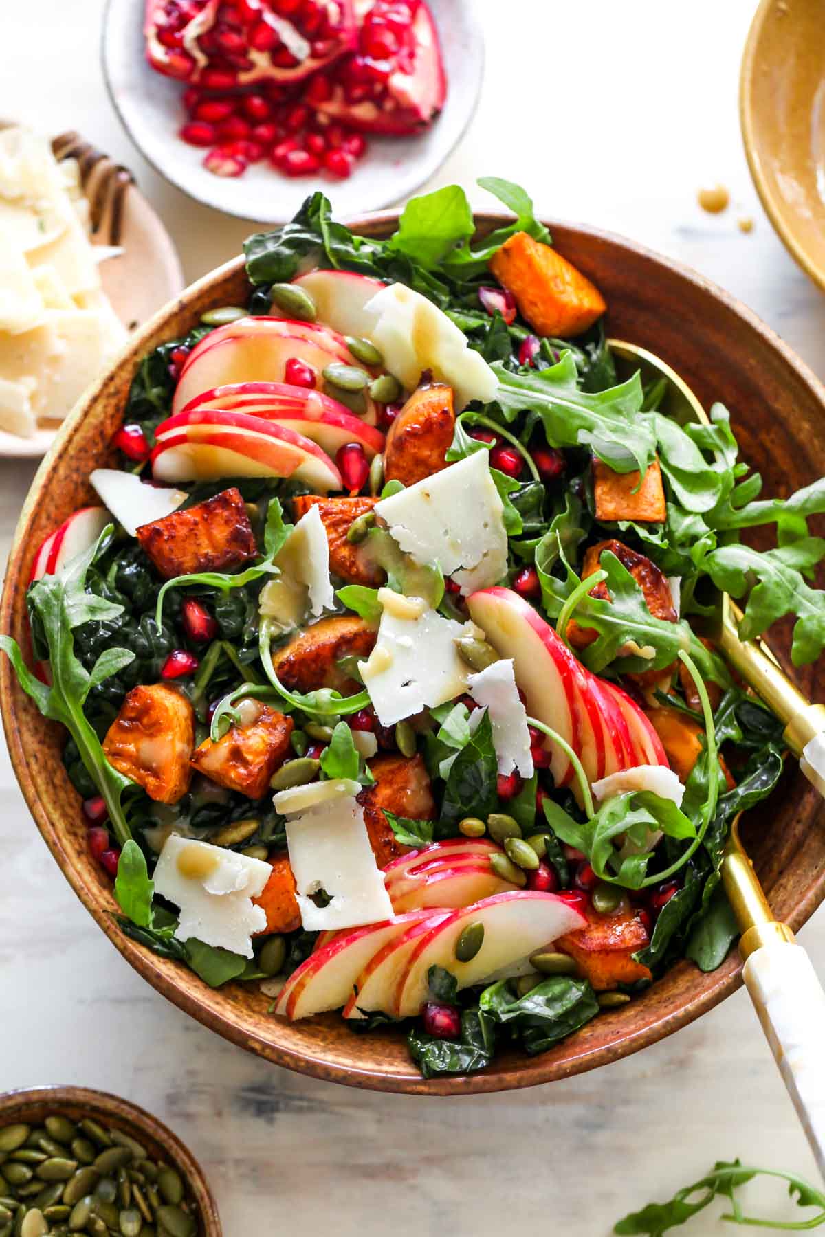 Autumn kale salad being mixed in a large gold bowl