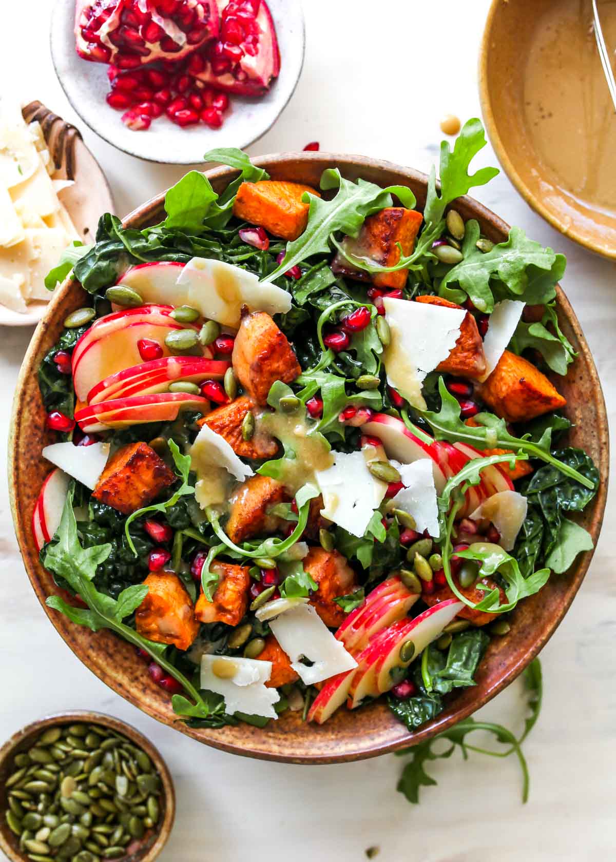 Kale salad topped with sweet potatoes, apples, and pomegranate seeds