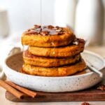 Stack of pumpkin protein pancakes being drizzled with syrup