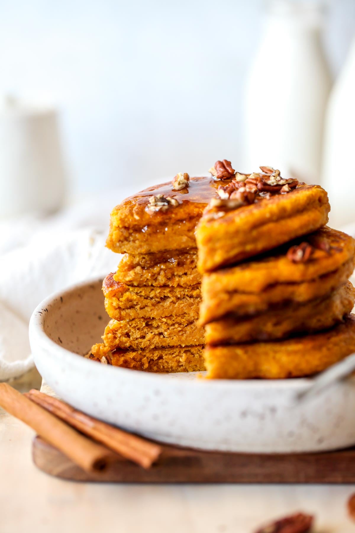 Stack of four pumpkin pancakes being sliced into to reveal fluffy insides.