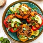 Quinoa and black bean stuffed peppers on a plate with toppings