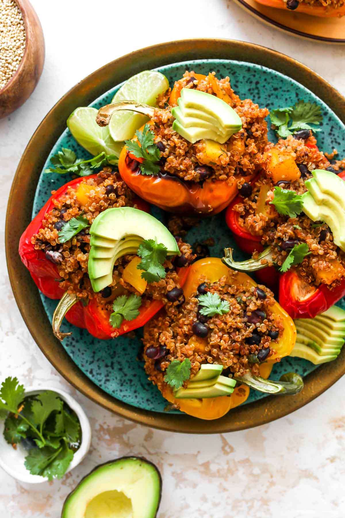 Quinoa-stuffed peppers on a blue plate topped with avocado slices