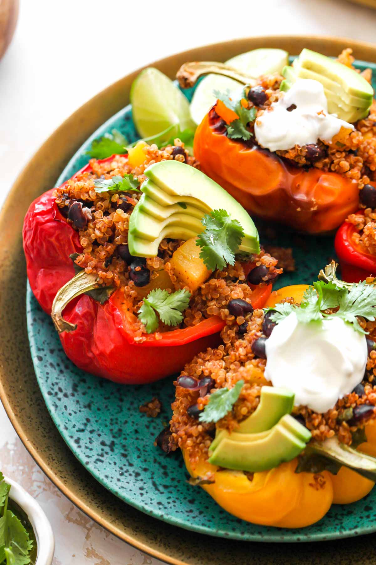 Vegetarian stuffed peppers on a blue plate topped with yogurt and avocado