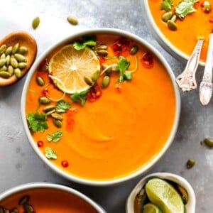 Thai pumpkin soup in a grey bowl topped with chili oil and herbs