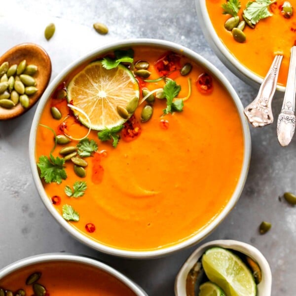 Thai pumpkin soup in a grey bowl topped with chili oil and herbs