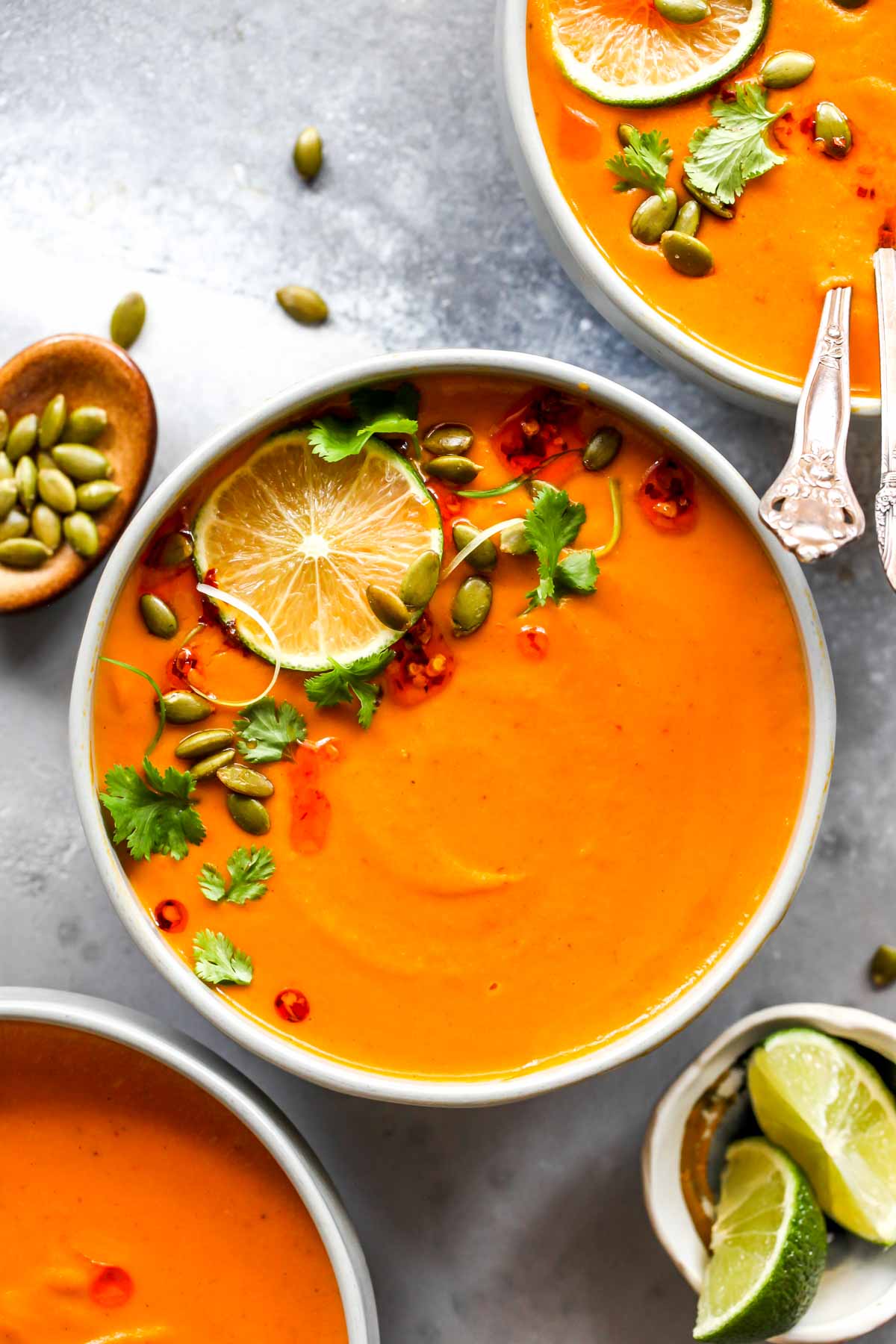 Creamy Thai Pumpkin Soup in a grey bowl topped with cilantro and lime