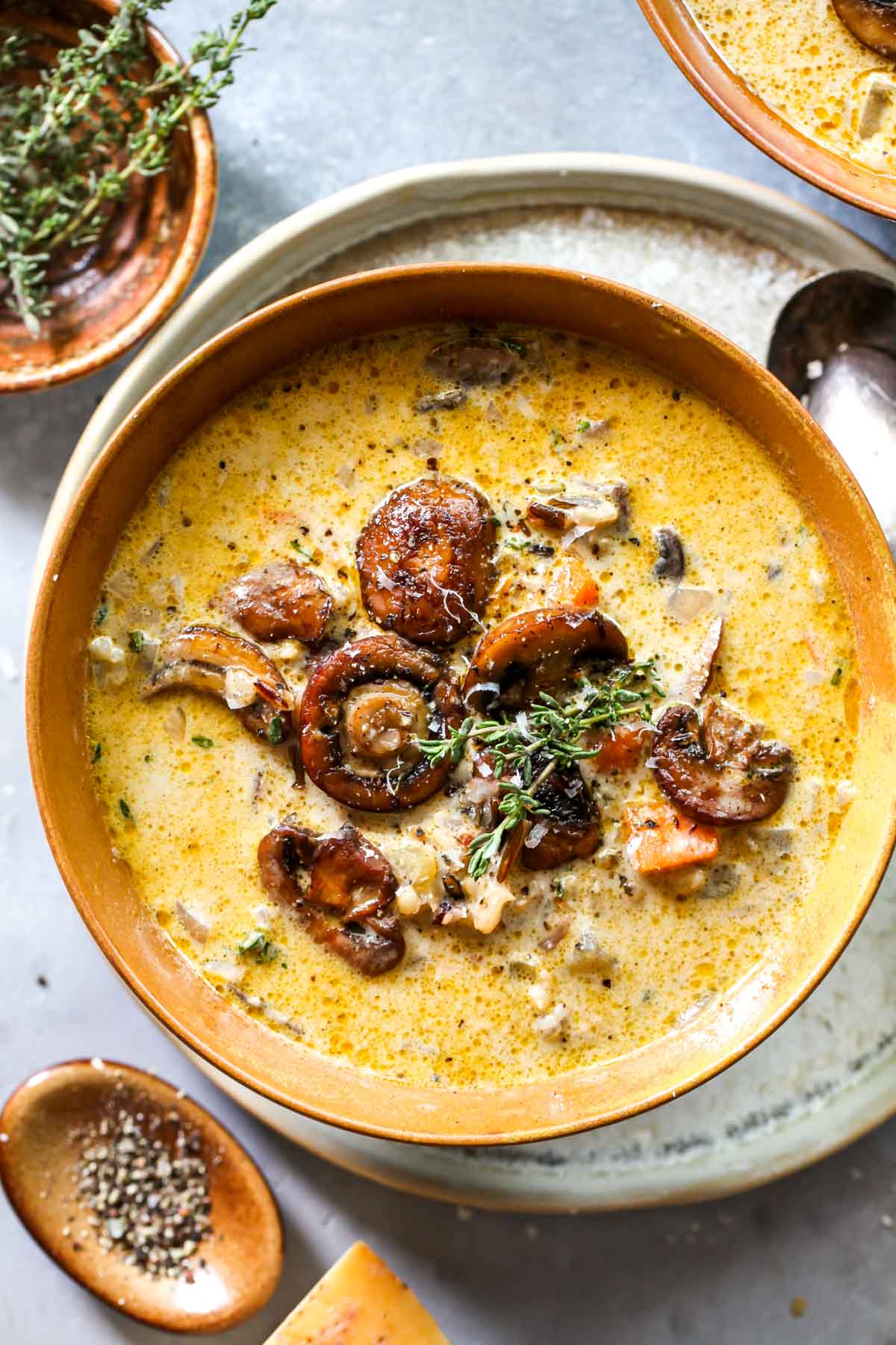 Wild rice and mushroom soup in a gold bowl topped with fresh thyme