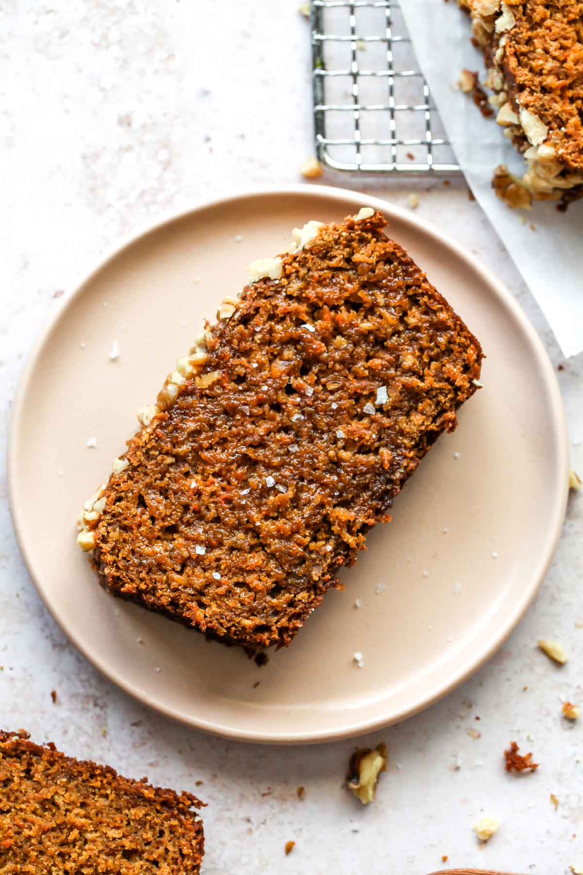 Slice of carrot apple bread on a pink plate topping with butter