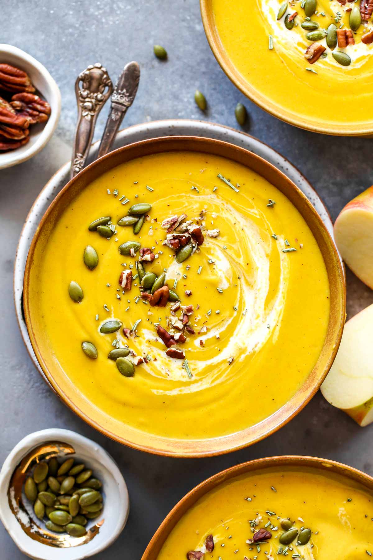 Butternut squash soup in gold bowls with pumpkin seed and pecan garnish
