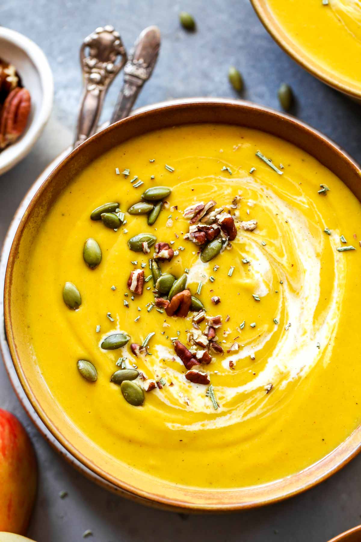 Close up of butternut squash soup in a bowl with a spoon resting on the side