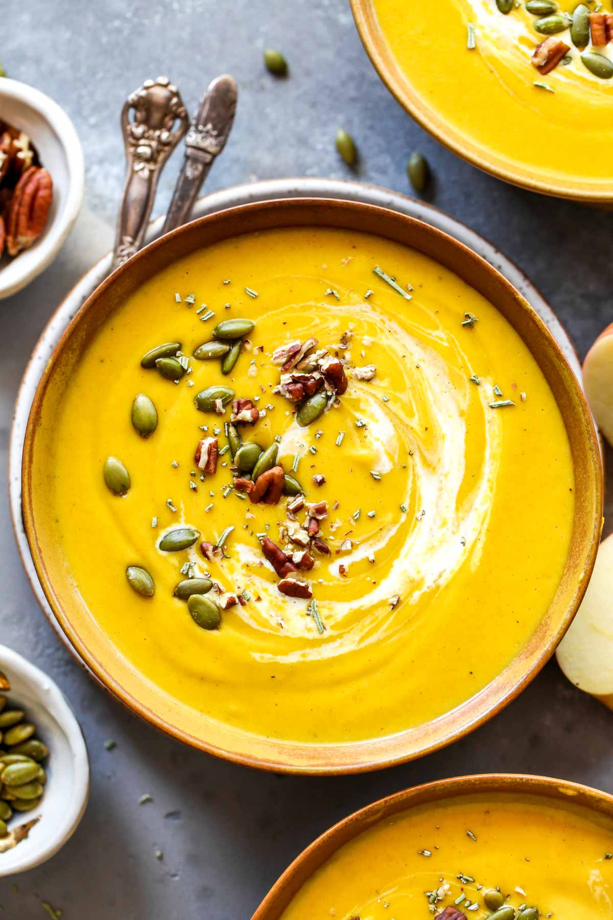 Creamy butternut squash topped with nuts in a gold bowl