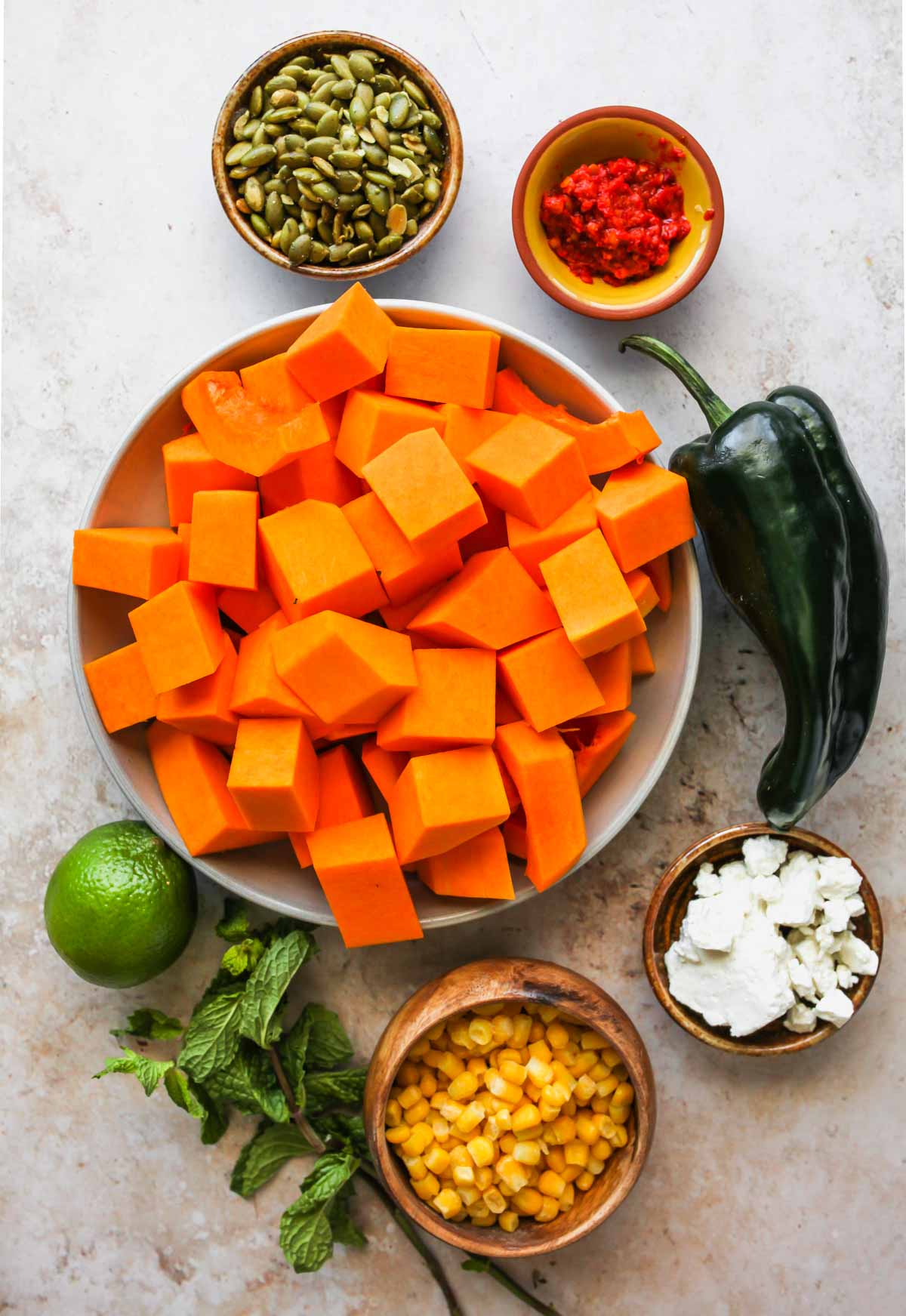 Butternut squash salad ingredients in separate bowls on a white board