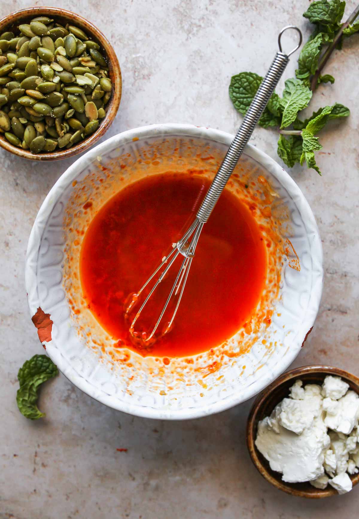 Harissa paste, lime juice, and olive oil being mixed in a bowl