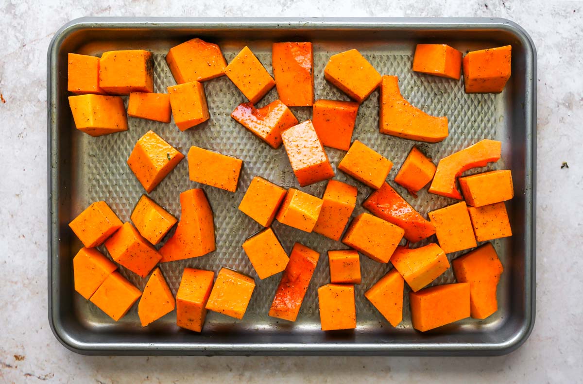Butternut squash cubes on a silver baking sheet