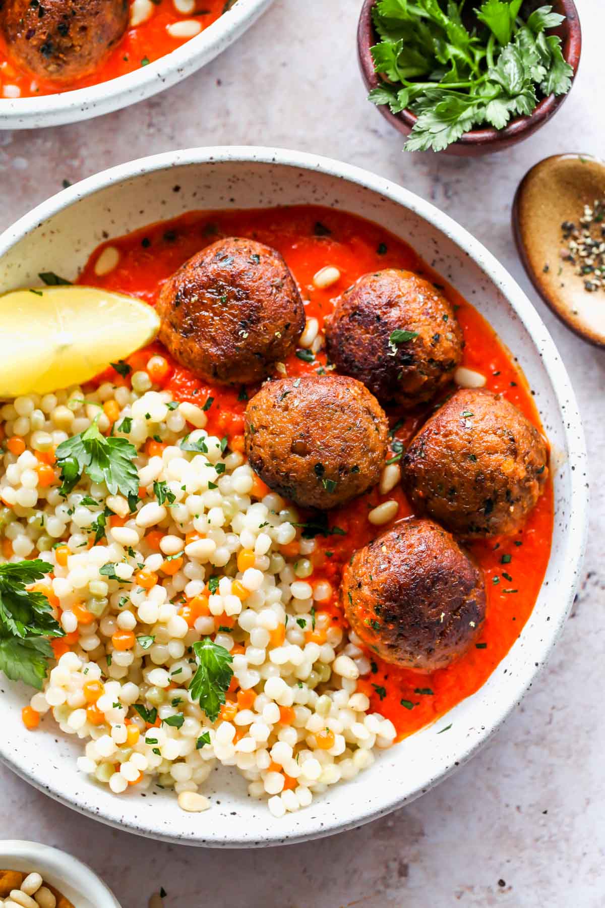 Lentil meatballs in roasted red pepper sauce with pearl couscous