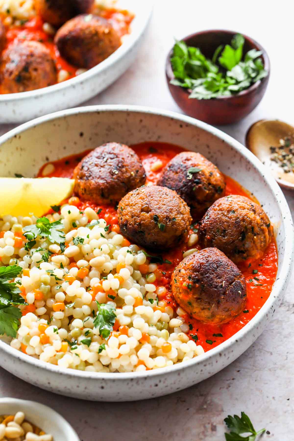 Couscous and veggie meatballs on a white plate topped with parsley