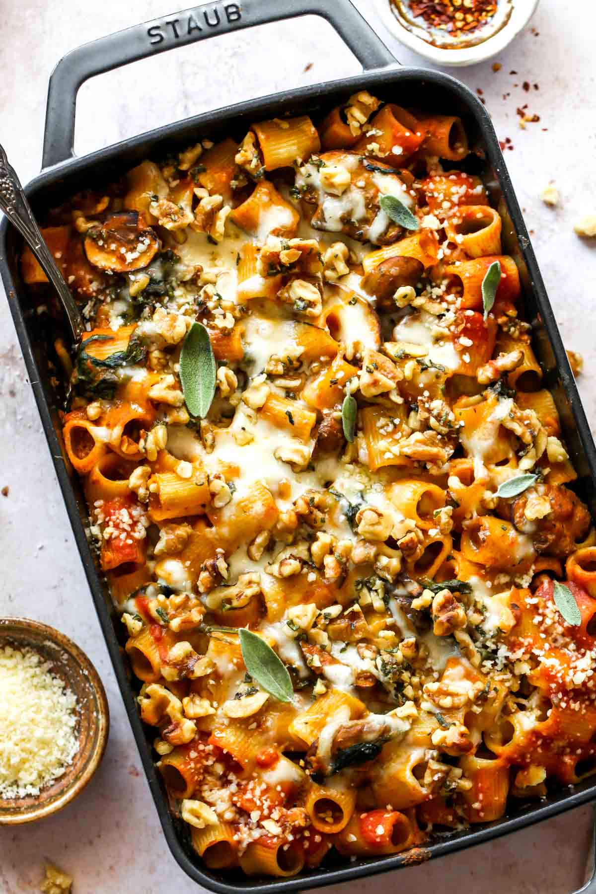 Cheesy baked pumpkin pasta styled in a large baking dish topped with a walnut-sage topping.