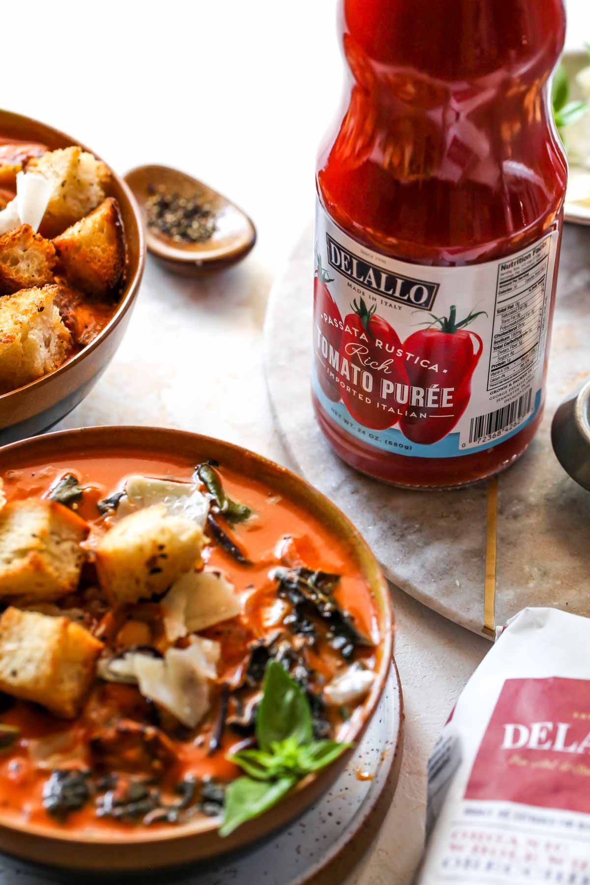 DeLallo Tomato Puree bottle next to a bowl of soup