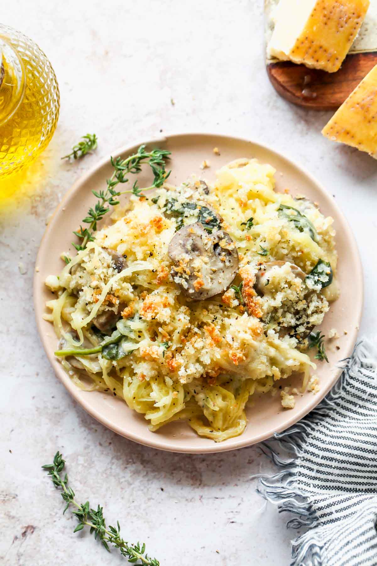 One serving of spaghetti squash on a pink plate topped with fresh thyme