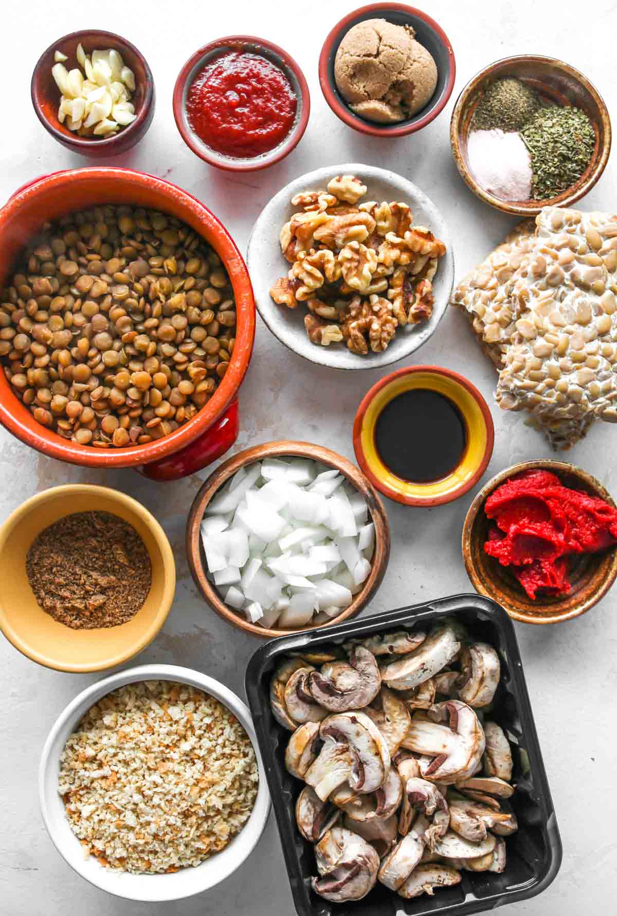 Vegetarian meatloaf ingredients in separate bowls on a white surface