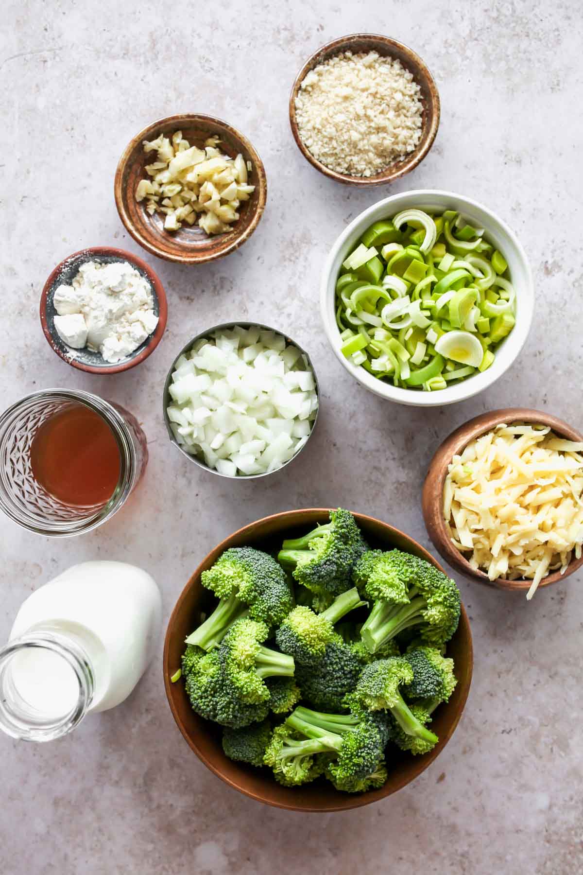 Ingredients for broccoli casserole in separate bowls on a white board