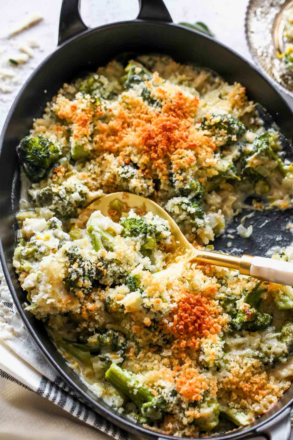 Spoon pulling out a serving of cheesy broccoli casserole