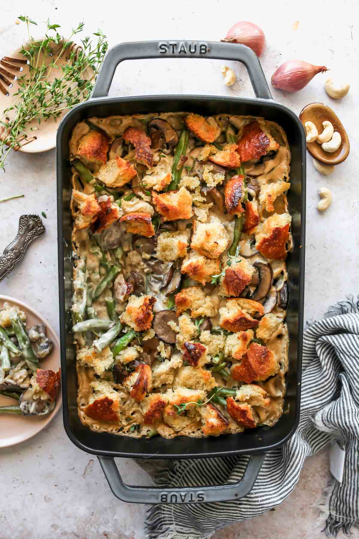 Vegan green bean casserole topped with sourdough croutons in a black baking dish.