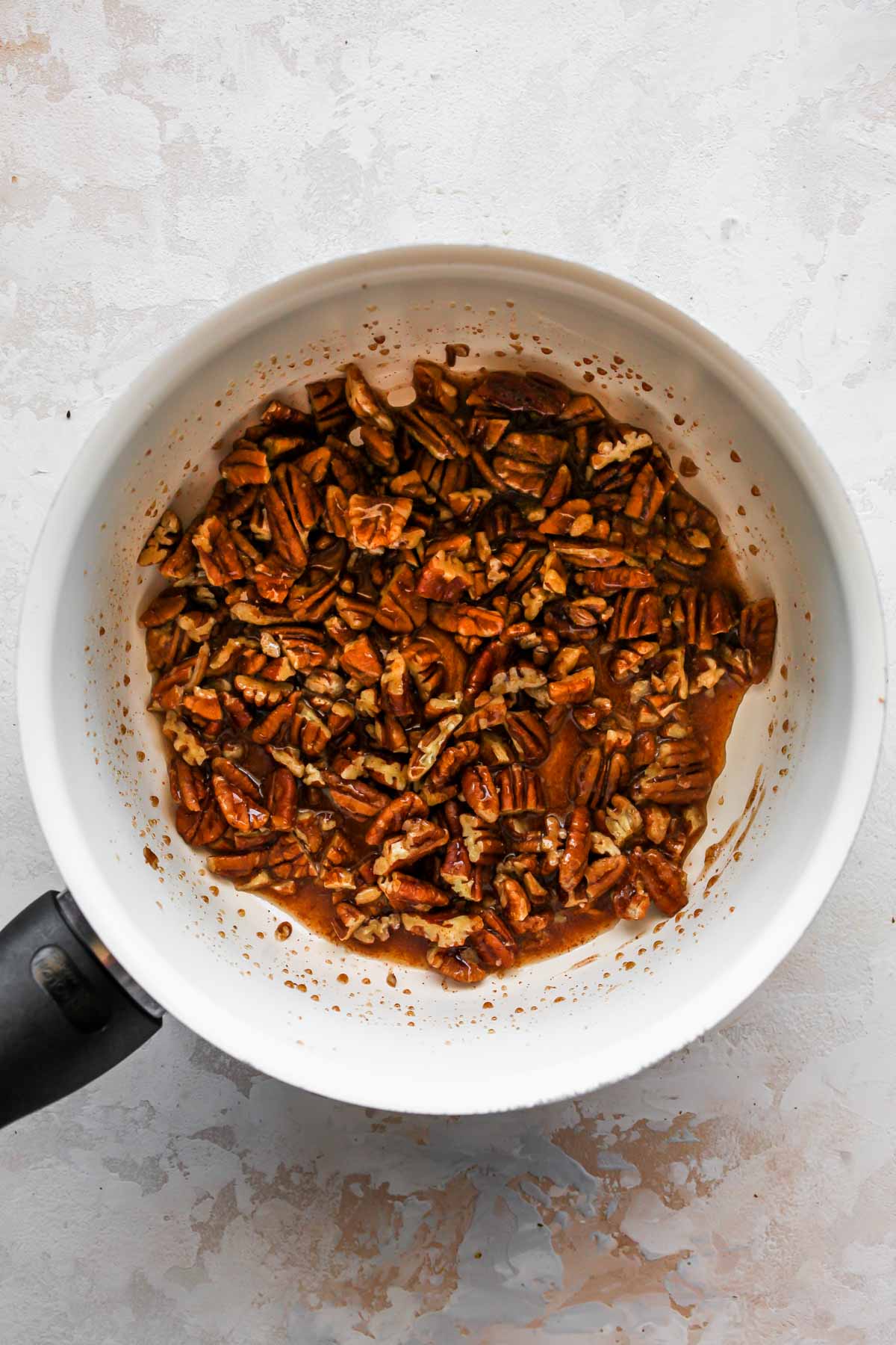 Pecans, maple syrup, and spice simmering in a saucepan