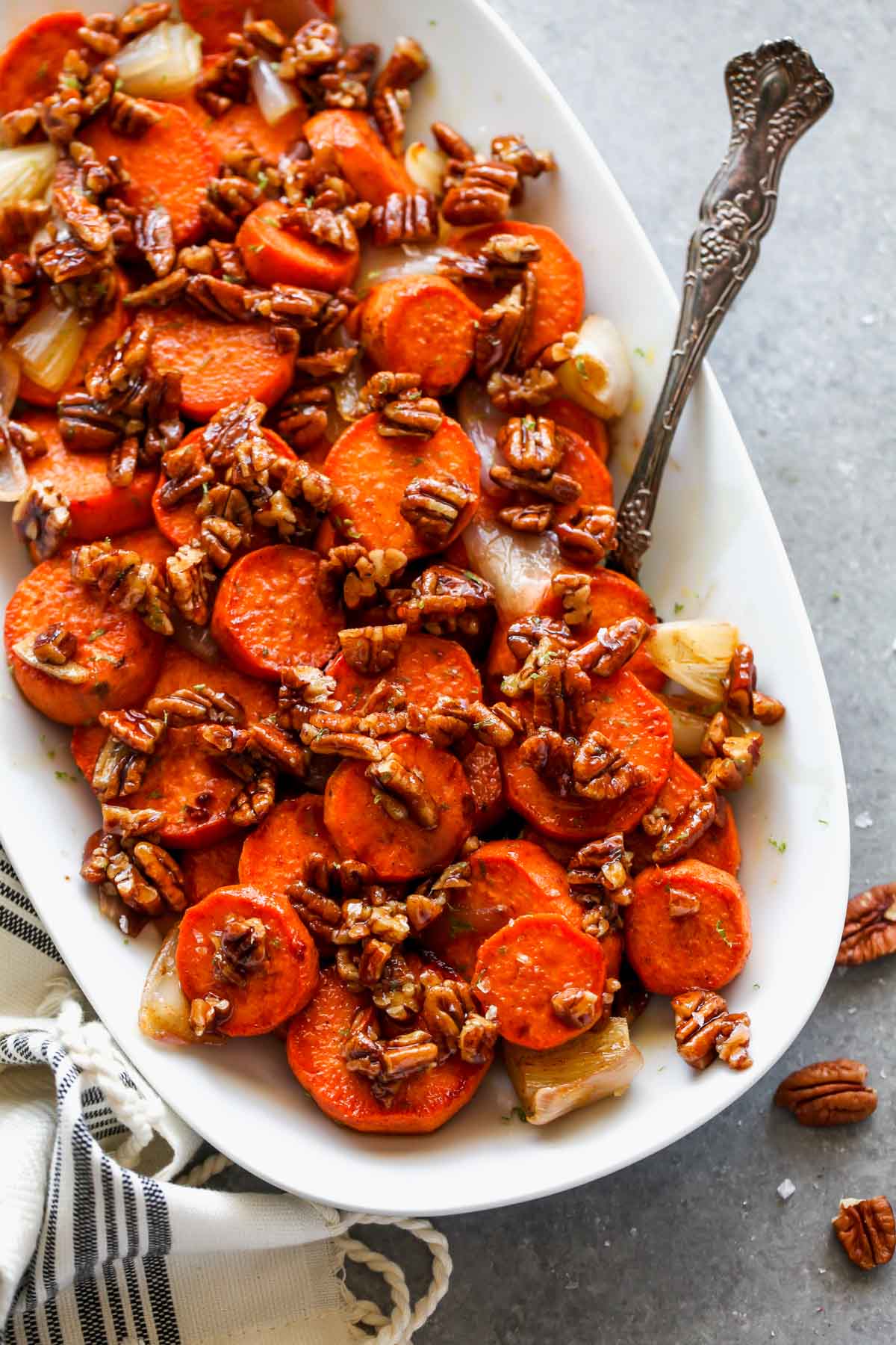 Sweet potato coins on a white platter topped with pecan praline