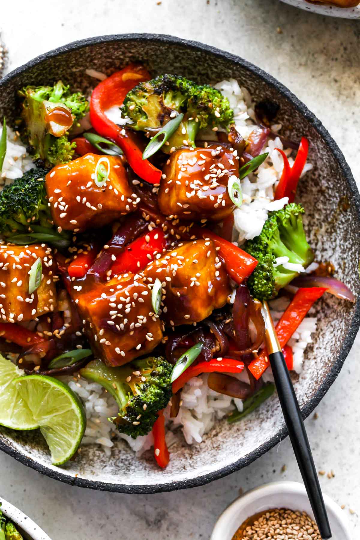 A fork taking a bite out of orange tofu bowls