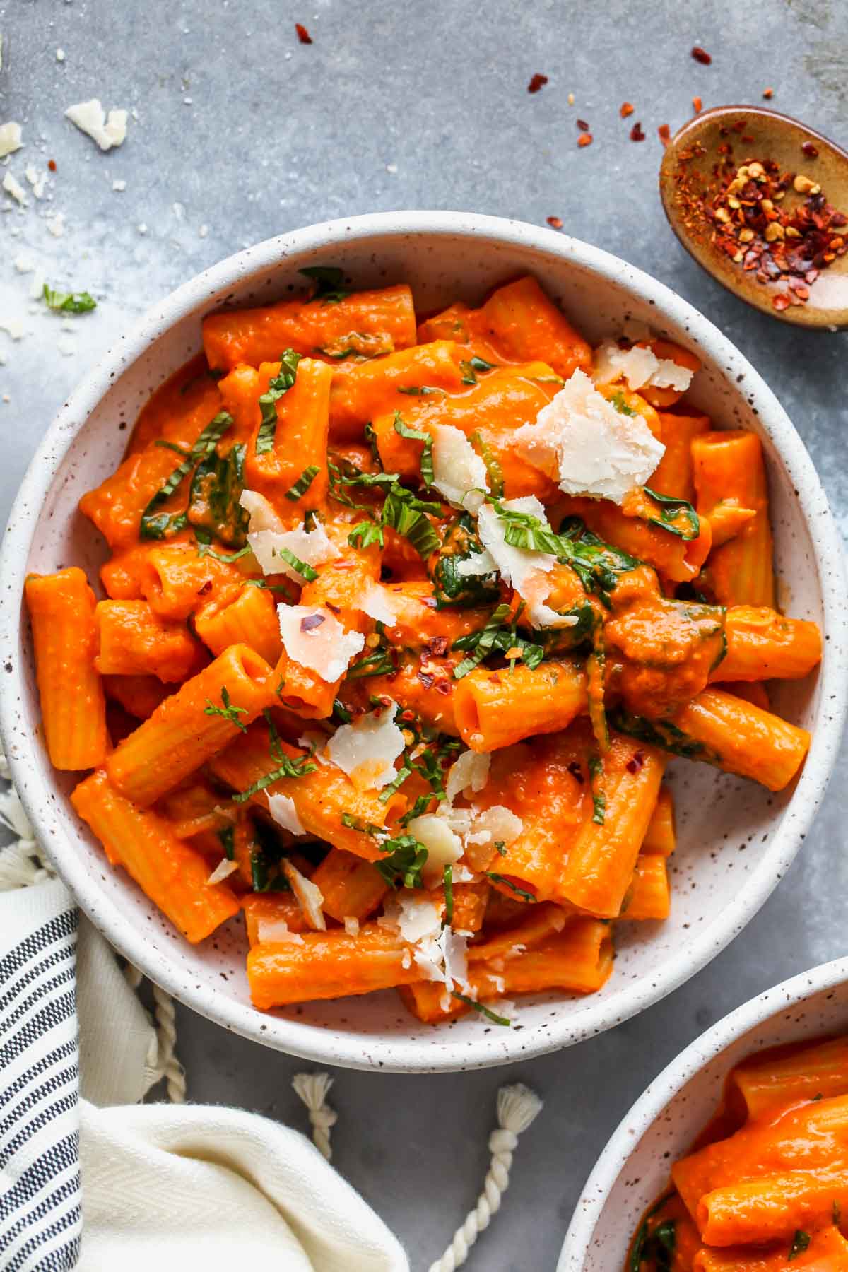 Rigatoni tossed in red pepper sauce in a white bowl