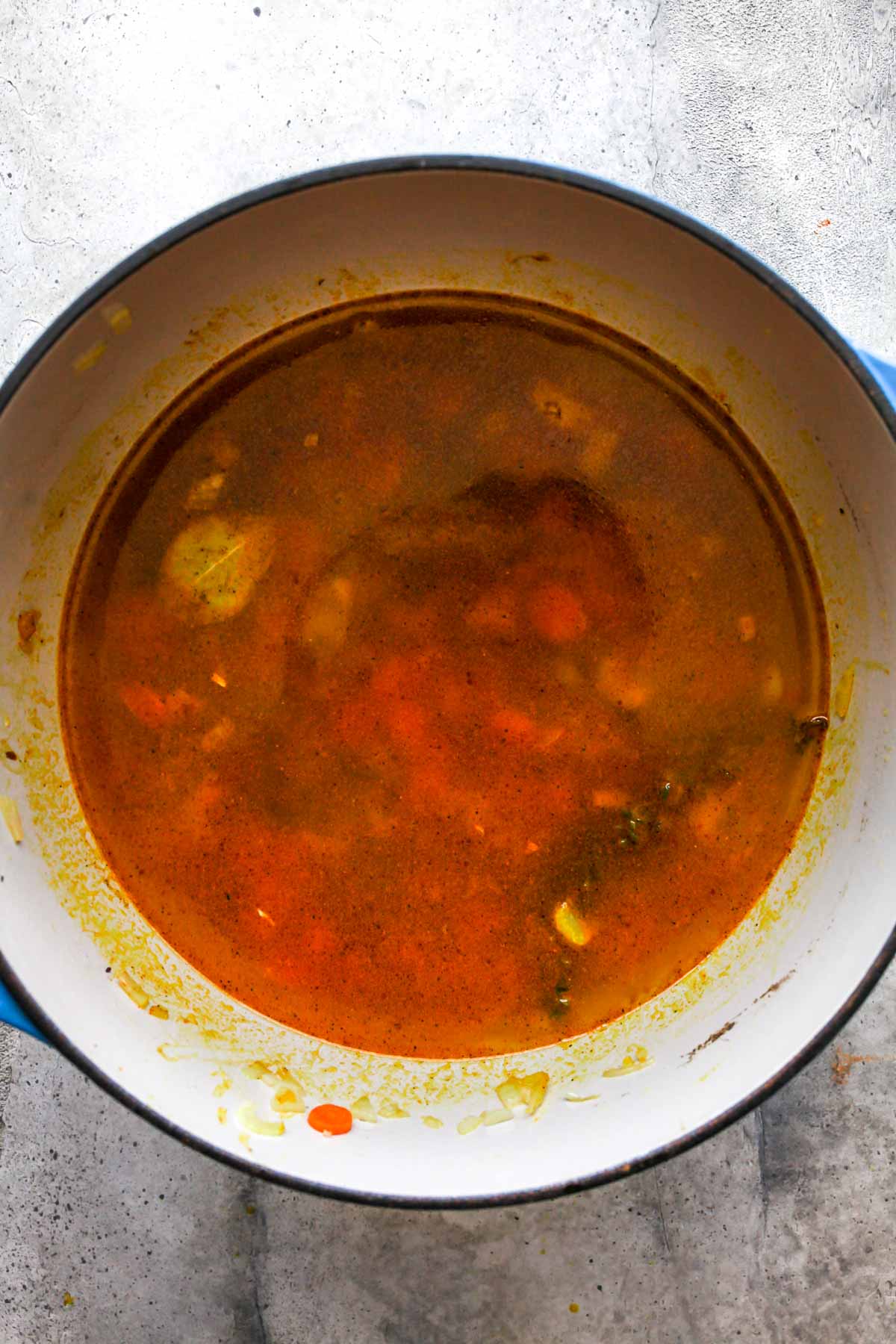 Broth being added to a Dutch oven