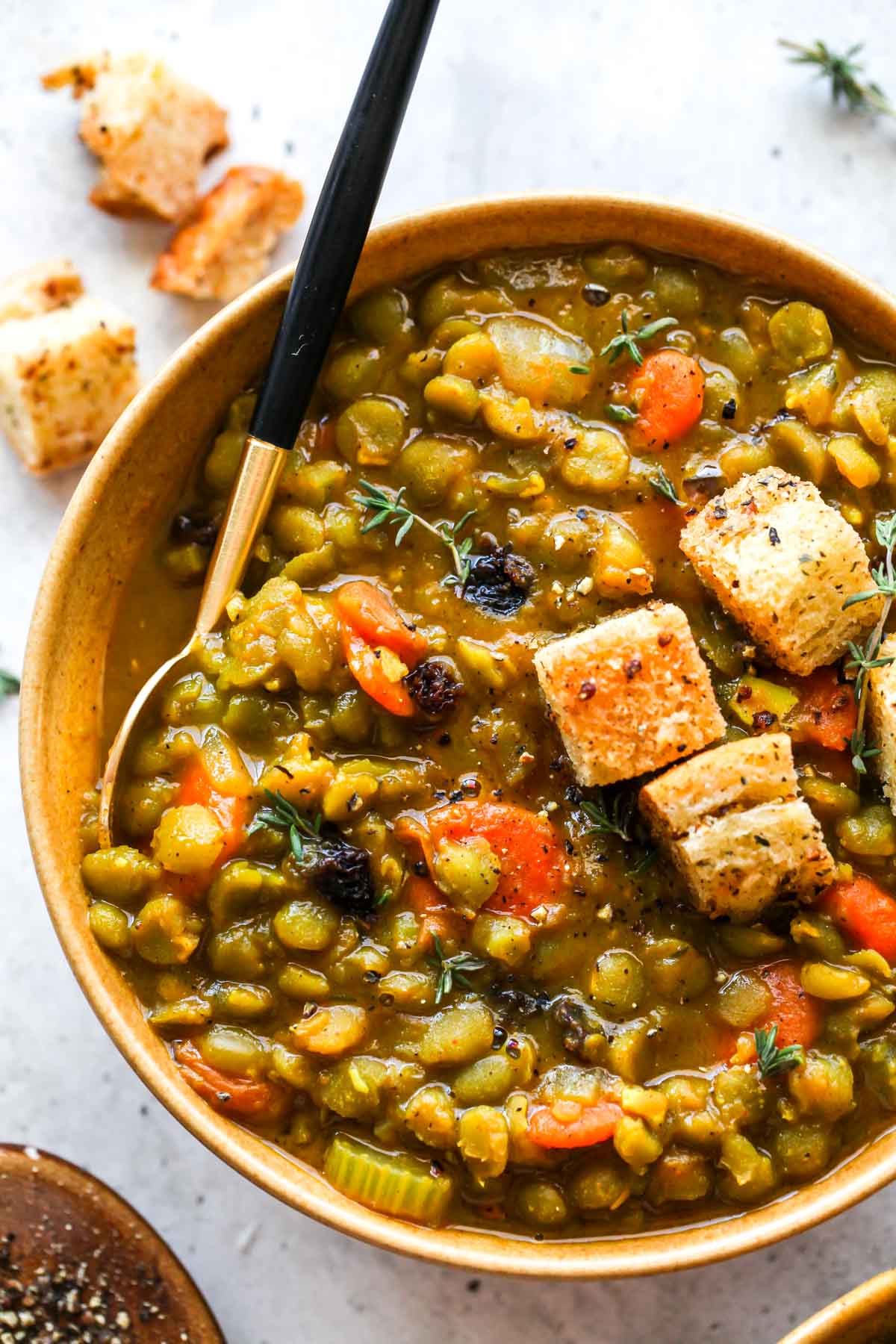Close up of split pea soup showing carrots, celery, and thyme