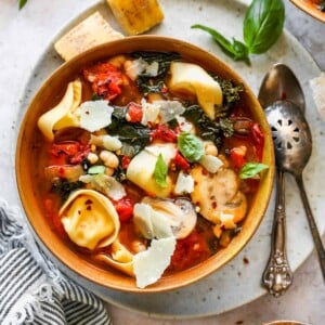 Tuscan tortellini and tomato soup in a gold bowl with basil garnish